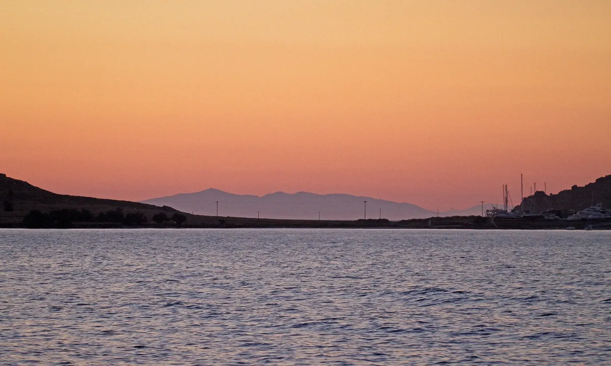 Boats leaving a Paros harbour in the morning light before a day cruise