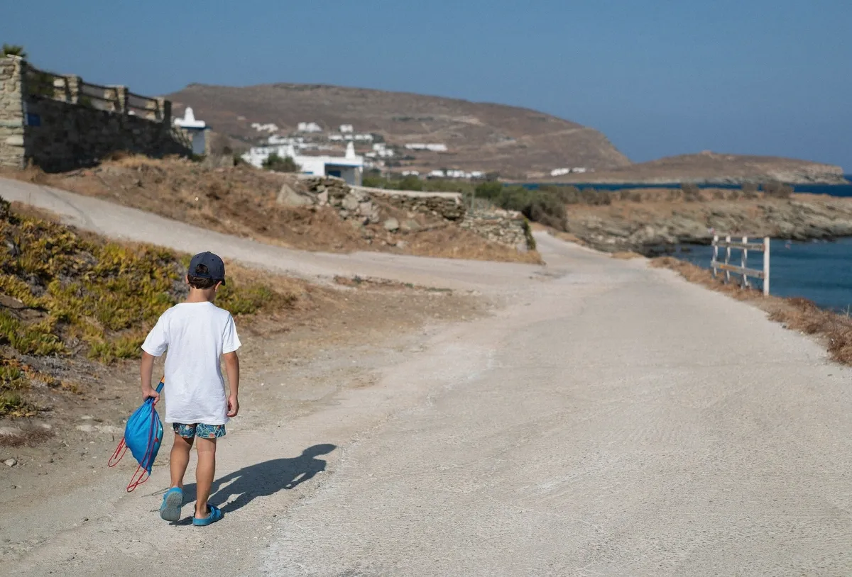 Traveller carrying snorkel gear and a bag toward the beach for a swim stop