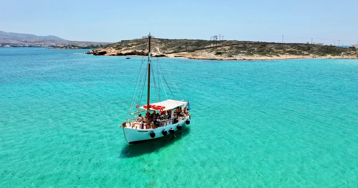 Wooden kaiki boat anchored in a turquoise bay on a Paros to Antiparos full-day cruise with seafood lunch